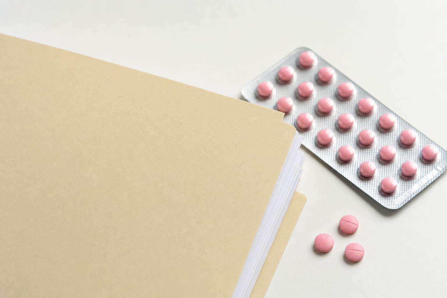Genetics report folder beside folic acid tablets on a clean desk, no people no readable PHI
