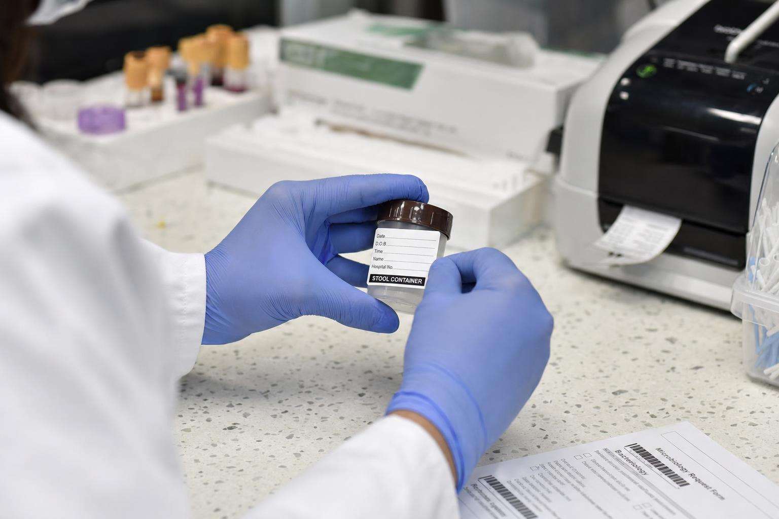 Clinical stool collection kit and lab form on a counter, no people