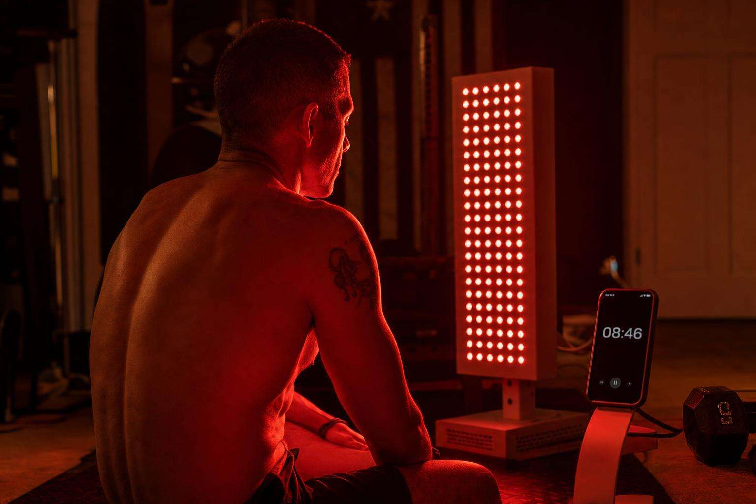 Red LED therapy panel glowing in a clean home gym corner, no people