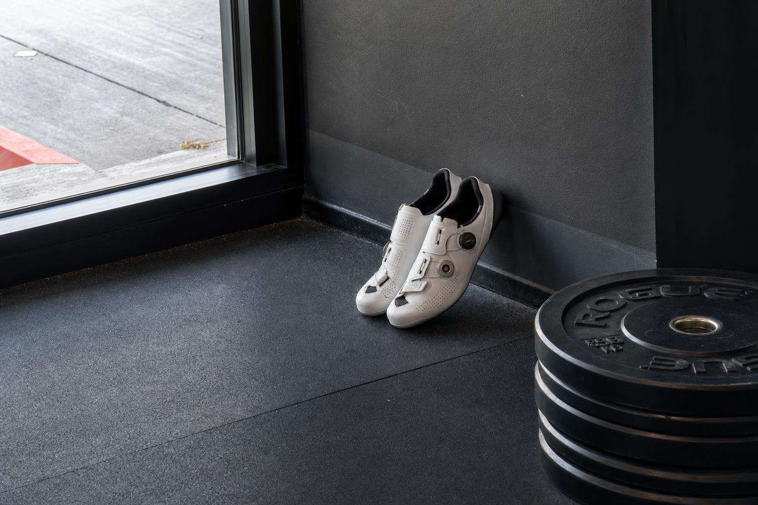 Running shoes next to barbell plates illustrating concurrent training, no people