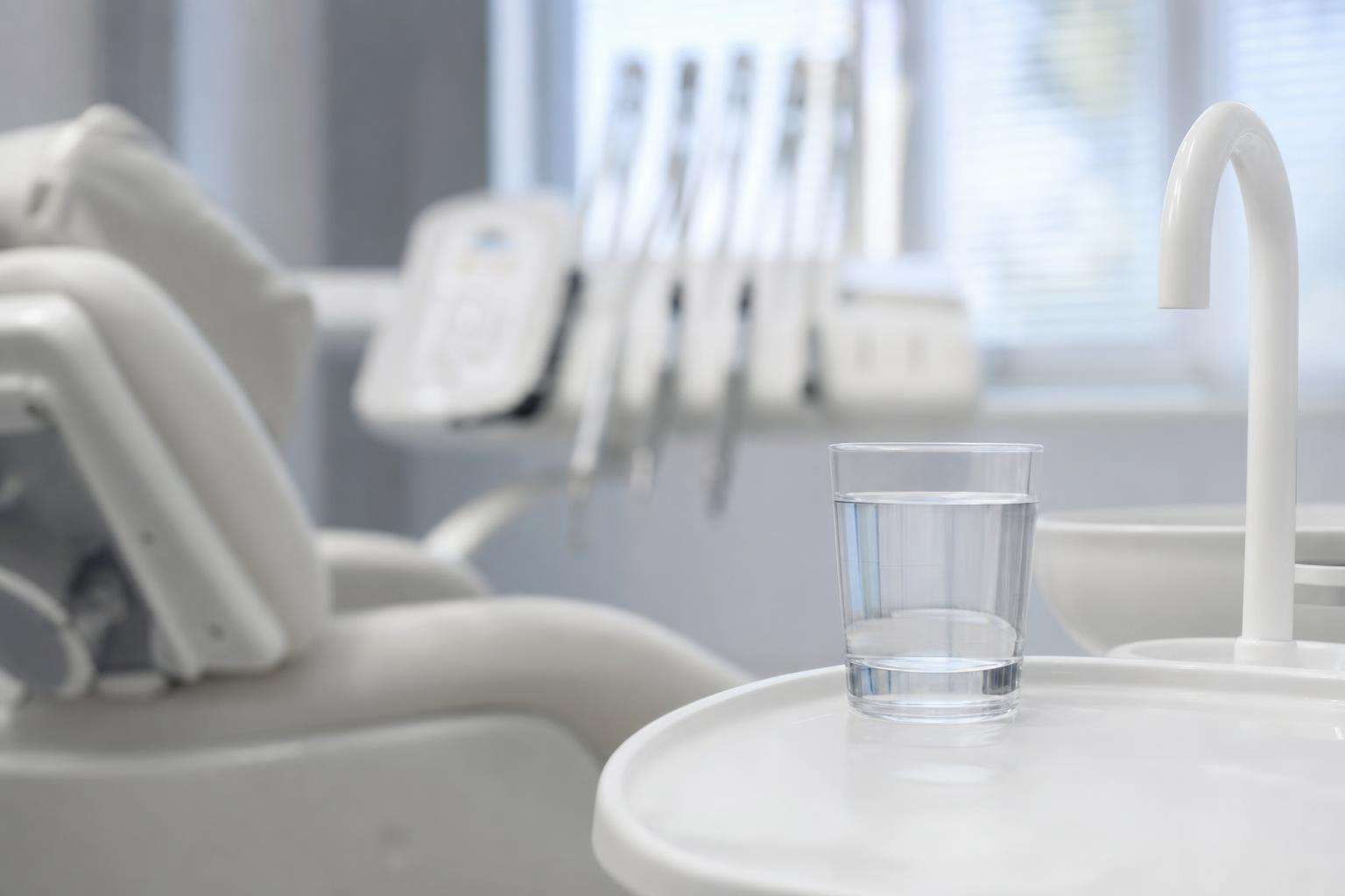 Dental office waiting area chair and water cooler silhouette, soft light, no people no brands