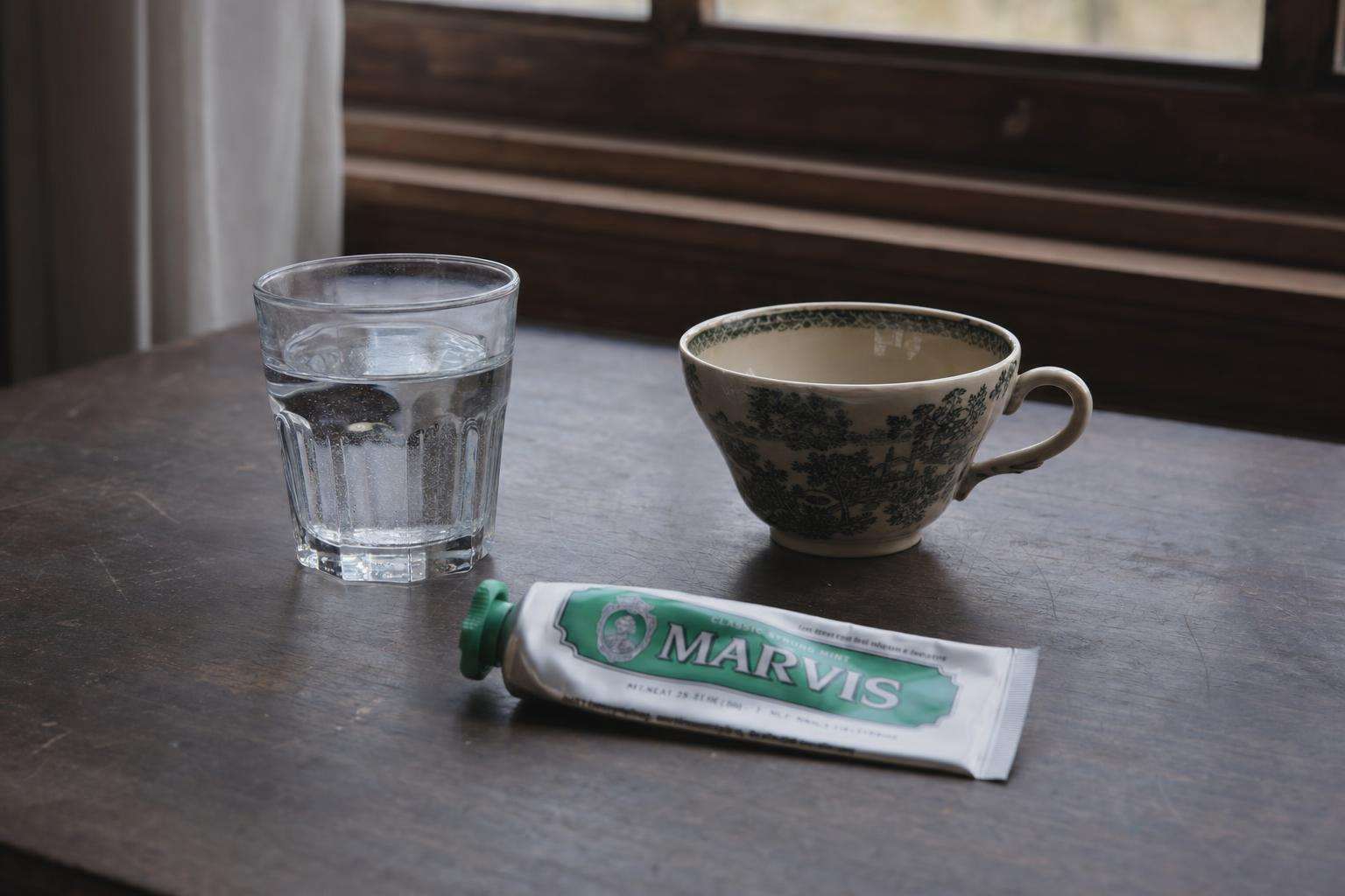 Water pitcher, tea cup, and children's toothpaste on kitchen counter, no people