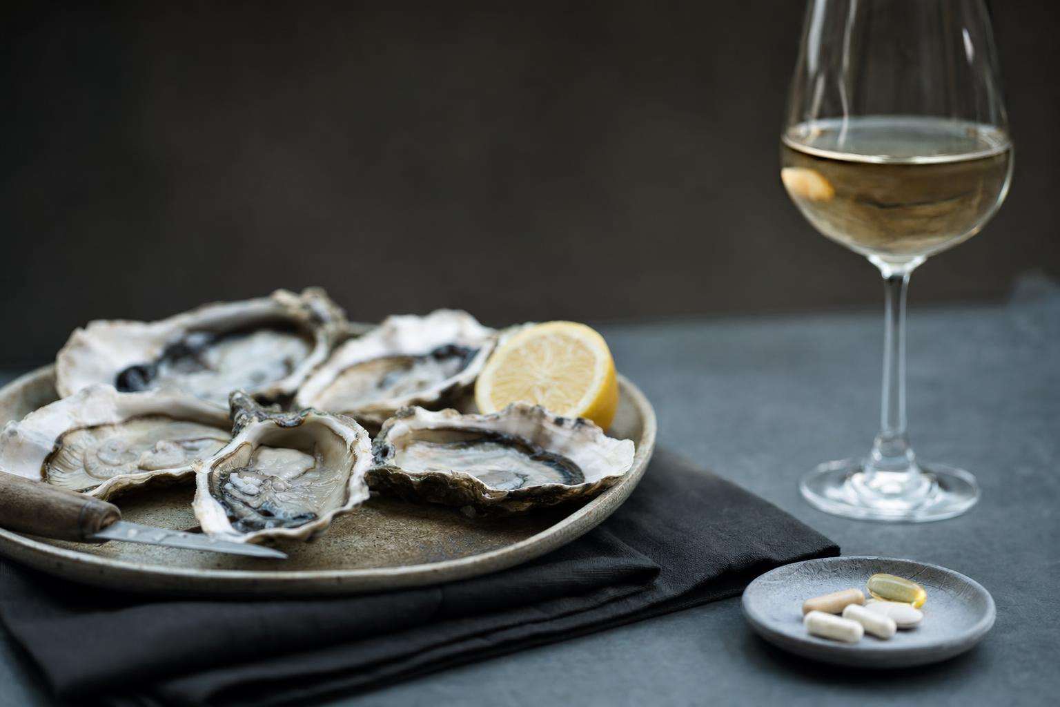Oysters plate with multivitamin bottle and wine glass props, no people