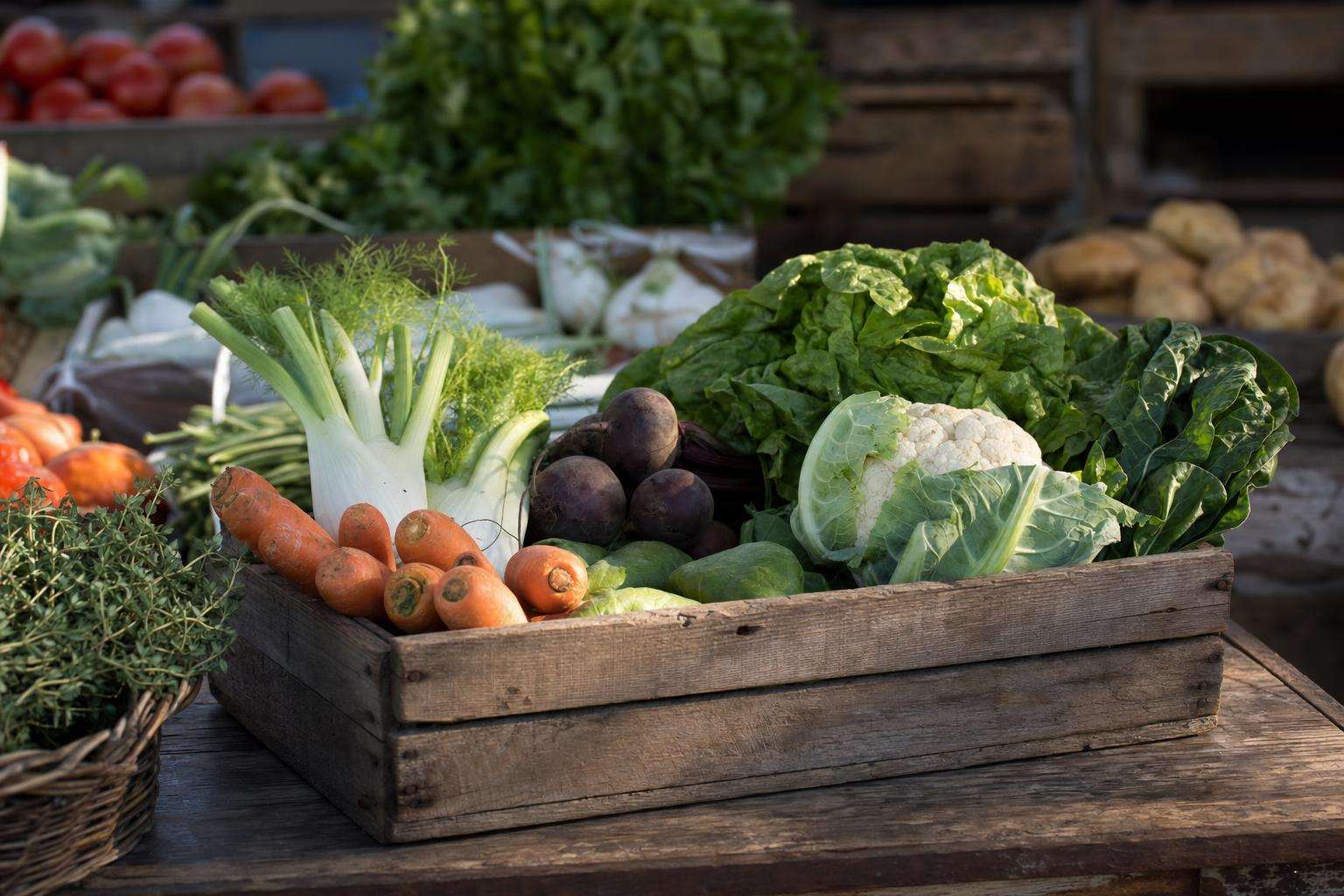 Farmers market produce crate beside empty supplement bottle crossed out, no people