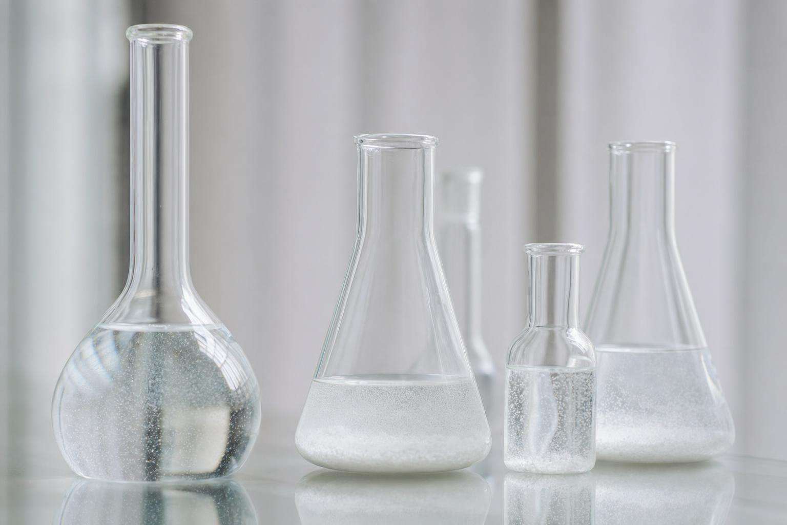 Abstract scientific still life with glass vessels and fine particles under soft lab light, no people