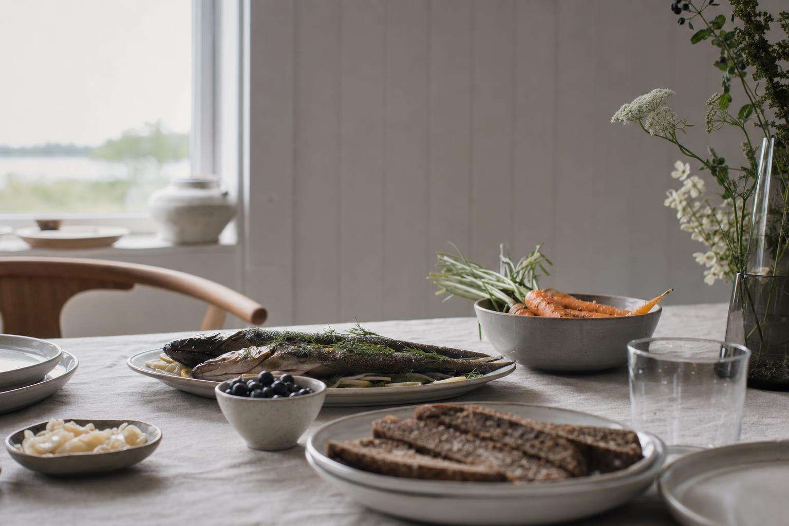Rye bread, fish, root vegetables, and berries on a Nordic-style table, no people