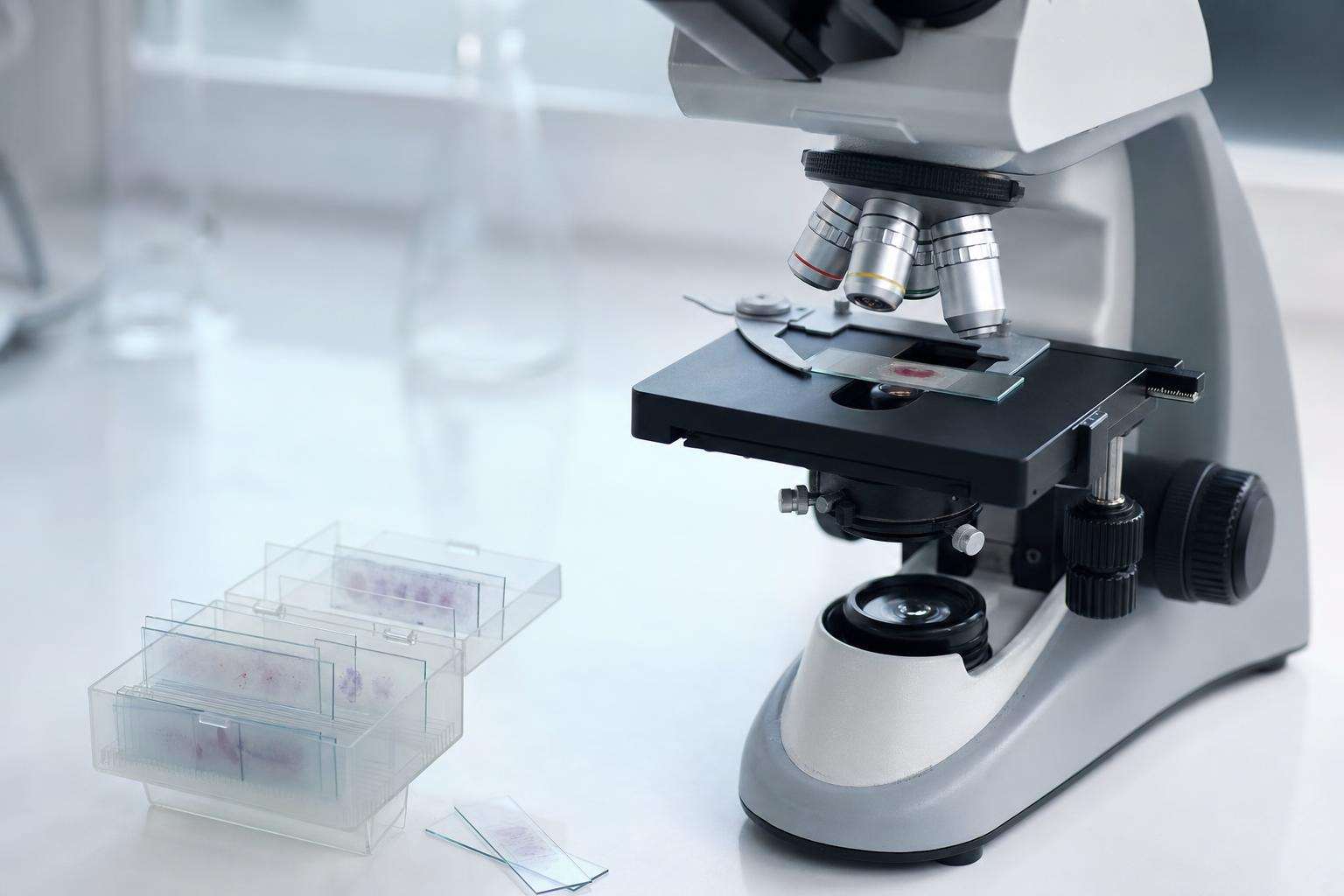 Microscope and lab slides on a clean clinical research bench, no people