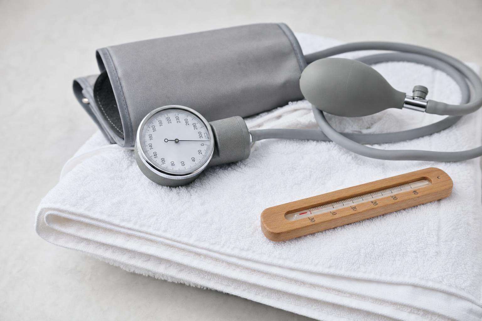 Blood pressure cuff beside wood sauna thermometer, no people