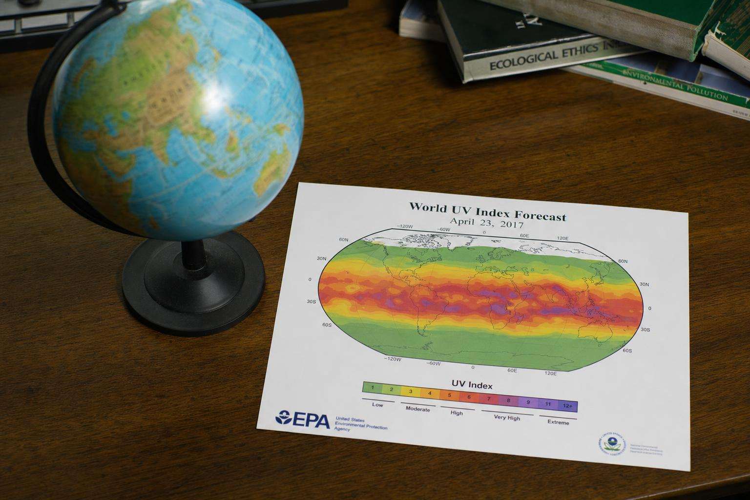 Globe with latitude lines beside UV index chart printout, no people