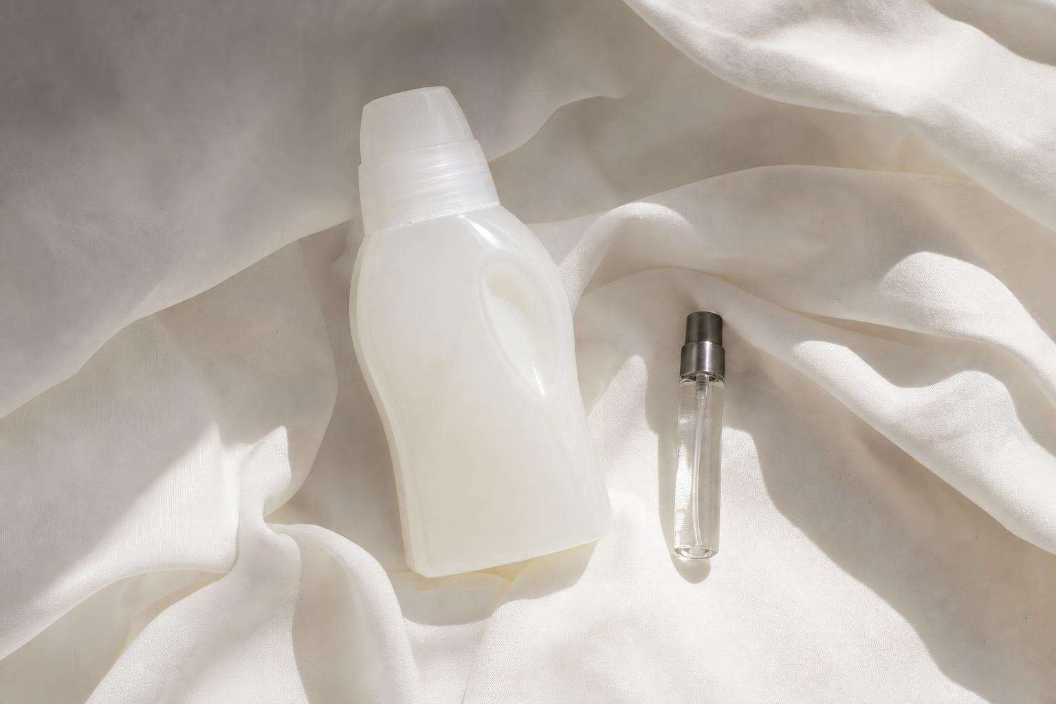 Laundry detergent bottle and perfume vial with fabric swatch, soft light, no people